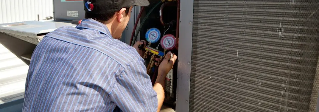HVAC technician servicing a condenser unit in Lee's Summit